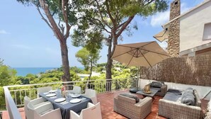 A terrace with a table set for dining, outdoor seating, and a view of the sea. - P67- Playetas- ServHouse (Oropesa)