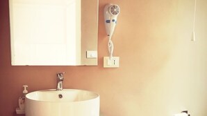 A bathroom with a round sink, a bidet, a mirror, and a hairdryer mounted on the wall. - Visitsicilia Donn Anna 2 (Castellammare del Golfo)