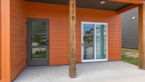 Un bâtiment avec une porte grise portant le numéro « 116 » et une porte vitrée avec un cadre blanc.