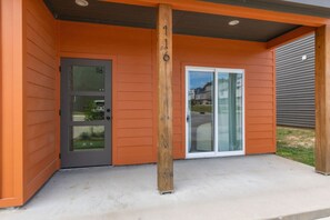 A building with a grey door labeled "116" and a glass door with a white frame.