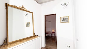A room with a large mirror, patterned floor tiles, a wooden bench, and a door leading to another room. - Visitsicilia Donn Anna (Castellammare del Golfo)