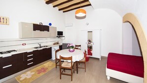 Una cocina compacta con armarios oscuros, una encimera blanca y una zona de comedor con una mesa y sillas.