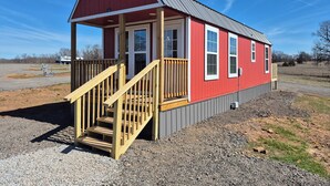 A red building with a porch and wooden stairs. - Redbud Tiny Home Resort (Big Cabin)