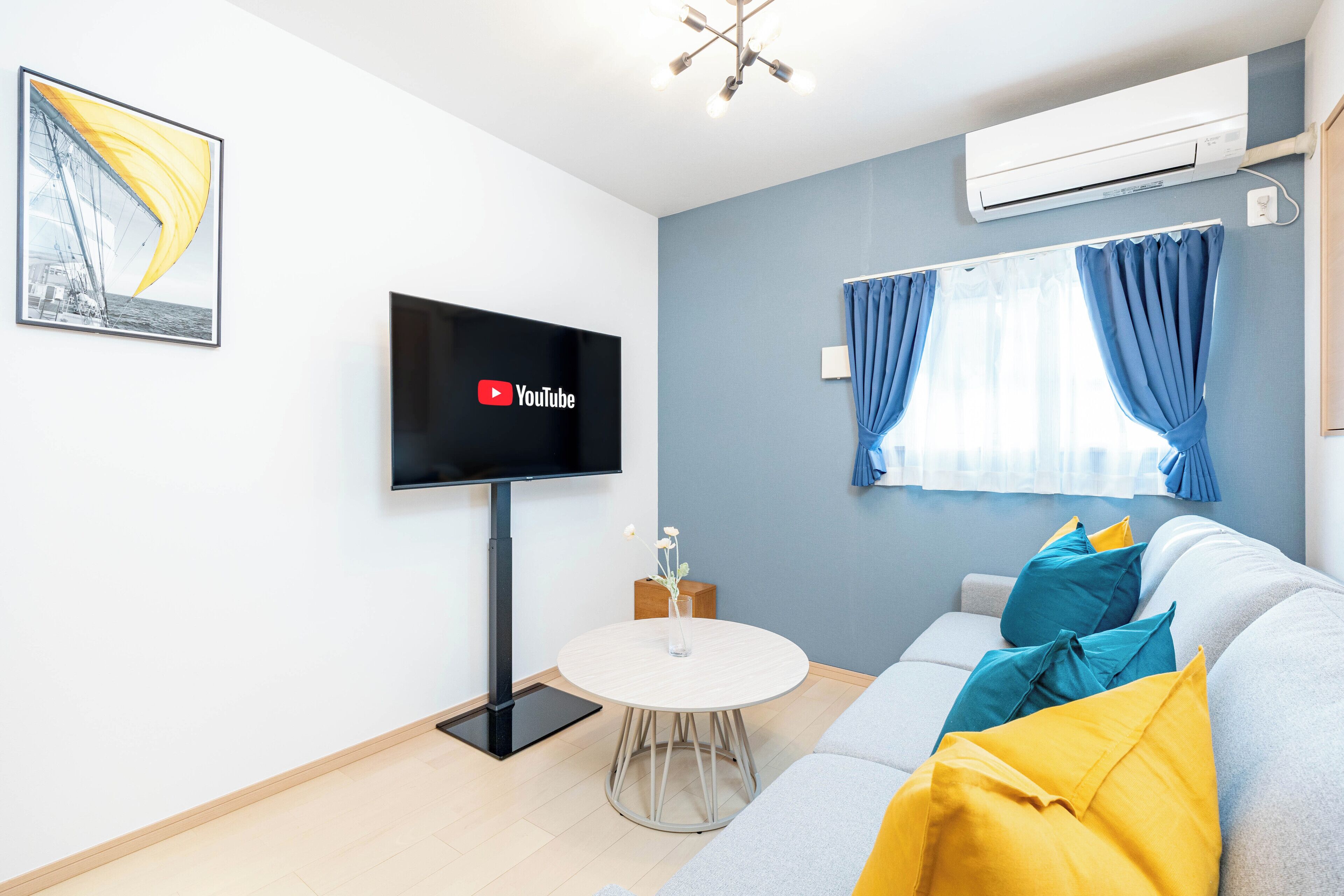 Una sala de estar moderna con un televisor de pantalla plana, una mesa redonda de centro y un sofá con cojines de colores.