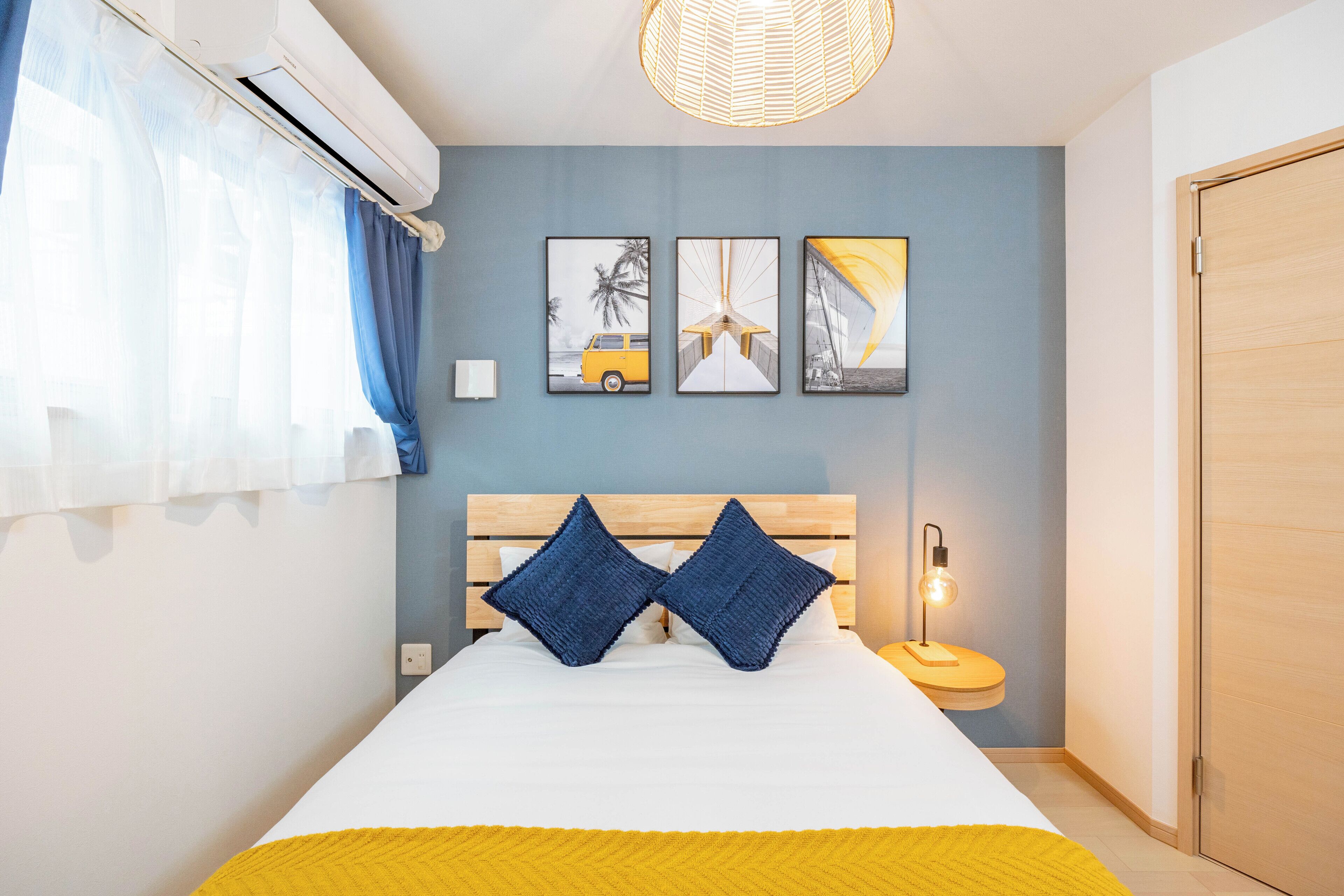 A bedroom with a bed, a bedside table with a lamp, and wall art.
