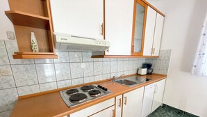 Een keuken met een fornuis, spoelbak en keukenkastjes.