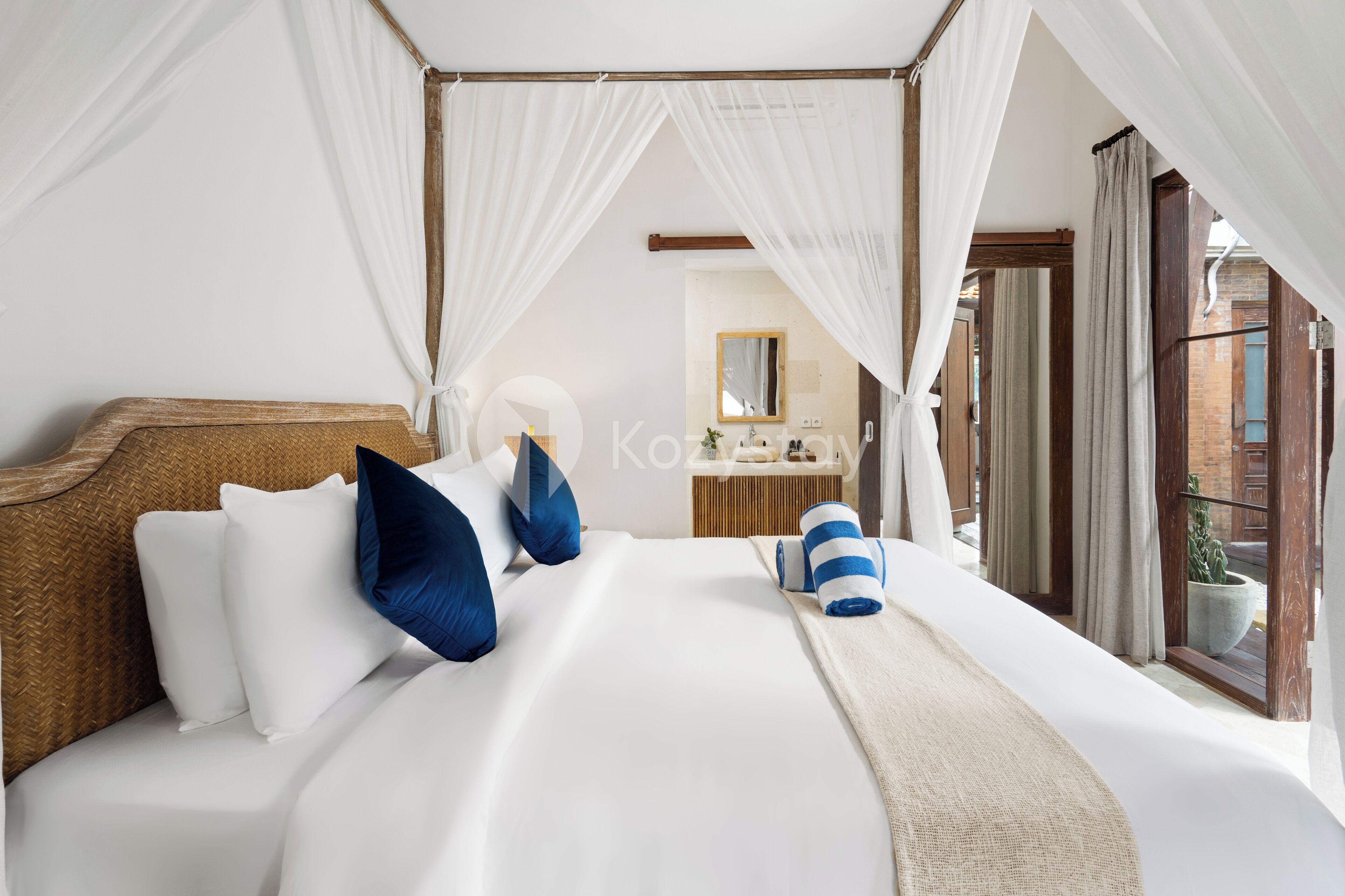 A bedroom with a four-poster bed, white bedding, and blue pillows.