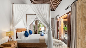 A bedroom with a four-poster bed, a bedside lamp, and a view of the garden.