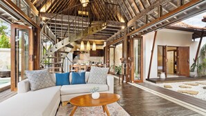 A spacious living area with a white sofa, a wooden coffee table, and a staircase leading to an upper level.