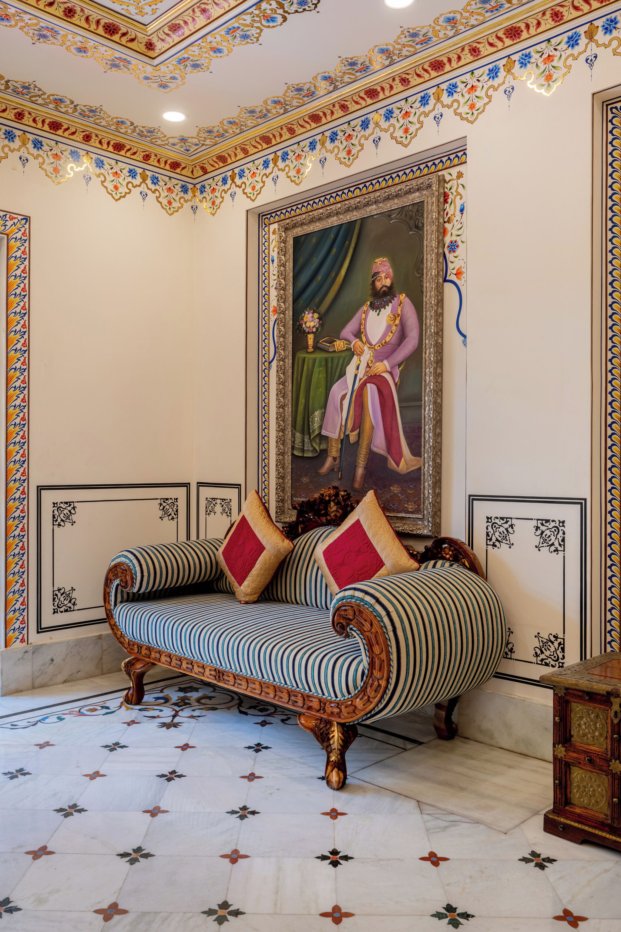 A room with a sofa, a framed portrait, and patterned walls.