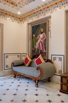Quarto com sofá, retrato emoldurado e paredes com padrão.
