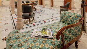 A luxurious lobby with ornate arches, a patterned floor, and a sofa with a magazine. - BRIJ CASTLE (Jaipur)