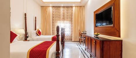 Una habitación de hotel con dos camas, un armario de madera, un televisor y un ventilador de techo.