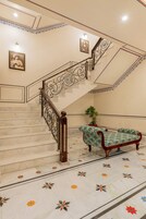 A marble staircase with ornate railings, a bench, and a potted plant.