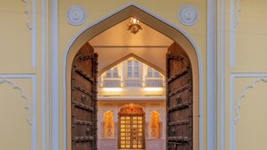 An arched entrance with a wooden door and a balcony with railings. - BRIJ CASTLE (Jaipur)
