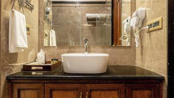 A bathroom with a marble wall, a sink, and wooden cabinets.