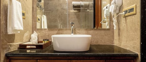 A bathroom with a marble wall, a sink, and wooden cabinets.