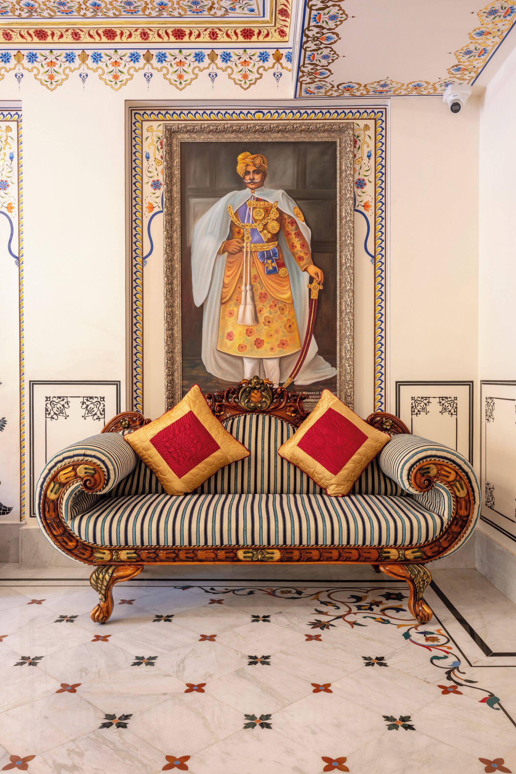 A room with a sofa, a framed portrait, and a patterned floor.