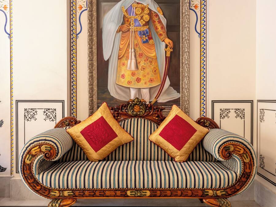 Una habitación con sofá, un retrato enmarcado y suelo estampado.