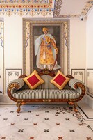 A room with a sofa, a framed portrait, and a patterned floor.