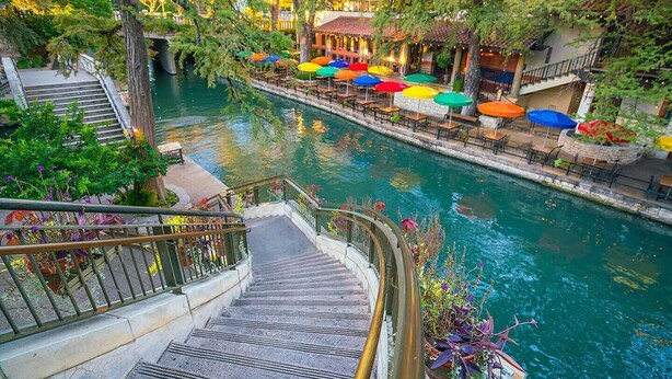 Een promenade langs de rivier met terras en een trap die naar het water leidt.