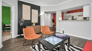 Een moderne woonkamer met twee oranje fauteuils, een zwarte salontafel en een spelbord.