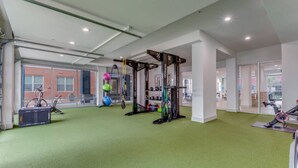 Een sportschool met trainingsapparatuur, een hometrainer en een vloer met groen tapijt.