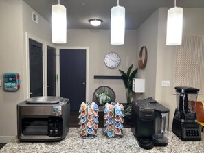 Een keuken met een magnetron, koffiezetapparaat, blender en een koffiepadapparaat.