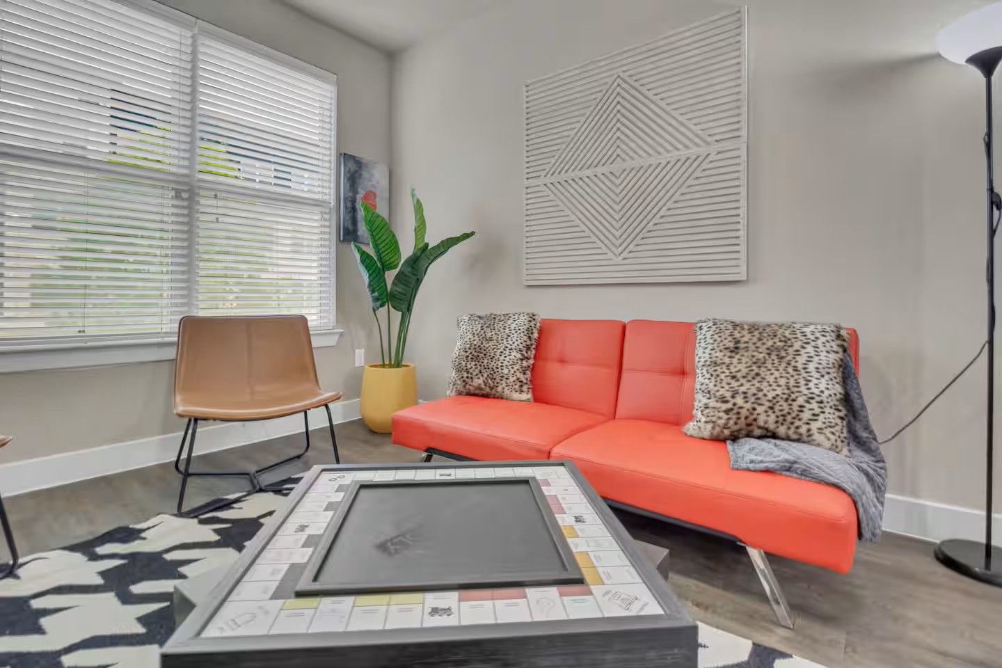 Ein Wohnzimmer mit einer Couch, einem Sessel, einem Couchtisch, einer Pflanze und einem Wandbild.