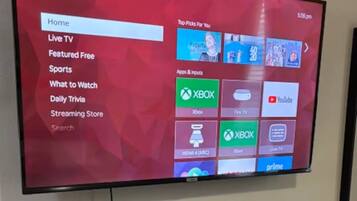 A television mounted on a wall displaying a Roku TV interface with various menu options.