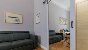 A modern living room with a sofa, a mirror, and a herringbone-patterned floor. - Studio Gar by Wonderful Italy (Turin)