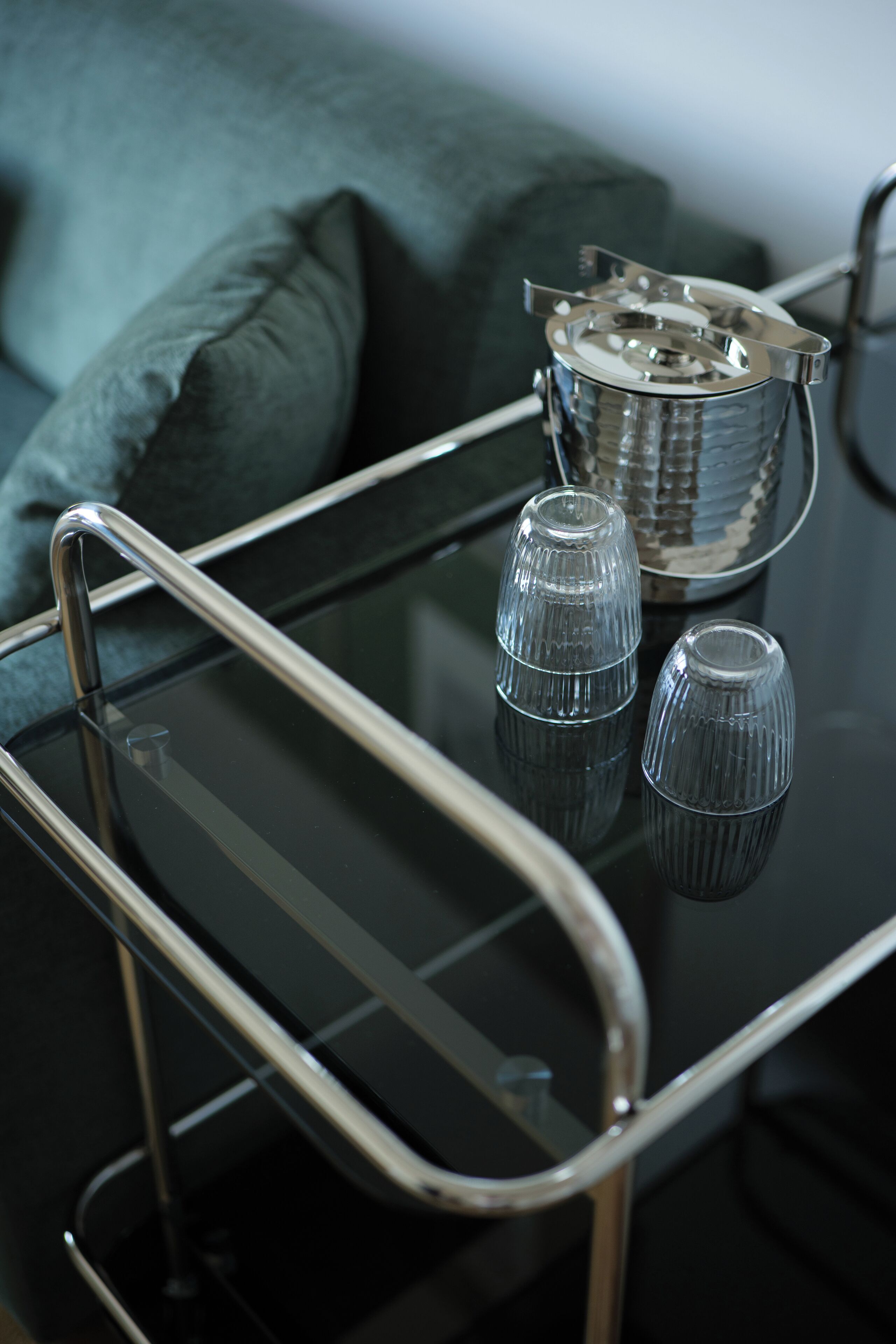 A glass table with metal legs and two clear glass vases on it.