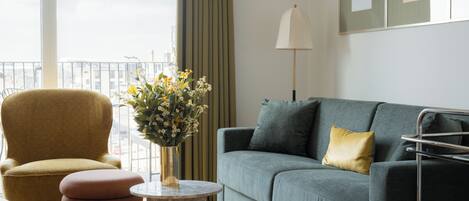 A modern living room with a green sofa, a yellow armchair, and a round coffee table with a vase of flowers.