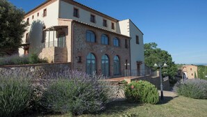 A two-story building with a stone facade, arched windows, and a balcony. - Nuovo Etruria Resort (Montepulciano)