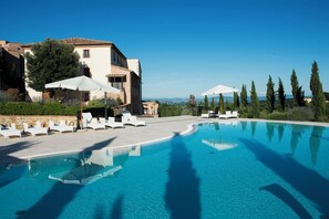 A swimming pool with lounge chairs and umbrellas, surrounded by buildings and trees. - Nuovo Etruria Resort (Montepulciano)
