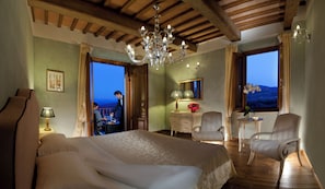 Un dormitorio con una cama grande, una araña, un aparador y vistas al exterior.