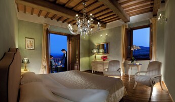Un dormitorio con una cama grande, una araña, un aparador y vistas al exterior.
