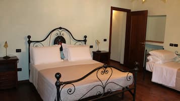 Una cama doble con cabecera, una mesita de noche y un espejo en la pared.