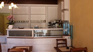 A kitchen with white cabinetry, a central island with a sink, and a dining area with two wooden chairs. - Nuovo Etruria Resort (Montepulciano)