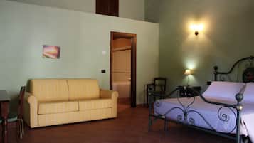 A room with a bed, a sofa, a chair, and a small table.