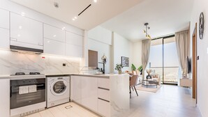 Une cuisine moderne dotée d’appareils électroménagers intégrés, un coin repas avec vue et une grande fenêtre agrémentée de rideaux.