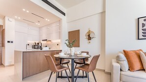 Une cuisine moderne avec des meubles blancs, un îlot central et un coin repas comprenant une table ronde et des chaises.