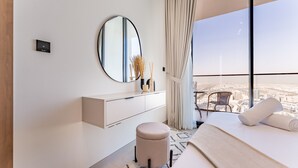 Une chambre d’hôtel moderne avec une grande fenêtre, un miroir rond, une table de chevet et un lit.