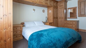 Ein Schlafzimmer mit einem Bett, Holzschränken, einer Kommode und einem Spiegel.