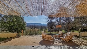 A patio with wicker furniture, a pergola, and a view of the countryside.
