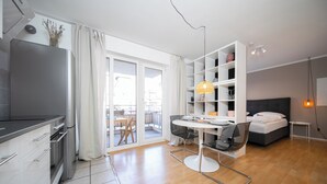 A modern, well-lit room with a kitchenette, a dining area, and a bedroom. - Favorite Stays - Neuss Furth (Neuss)