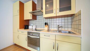 A kitchen with light-colored cabinets, a stainless steel oven, a sink, and a coffee maker.