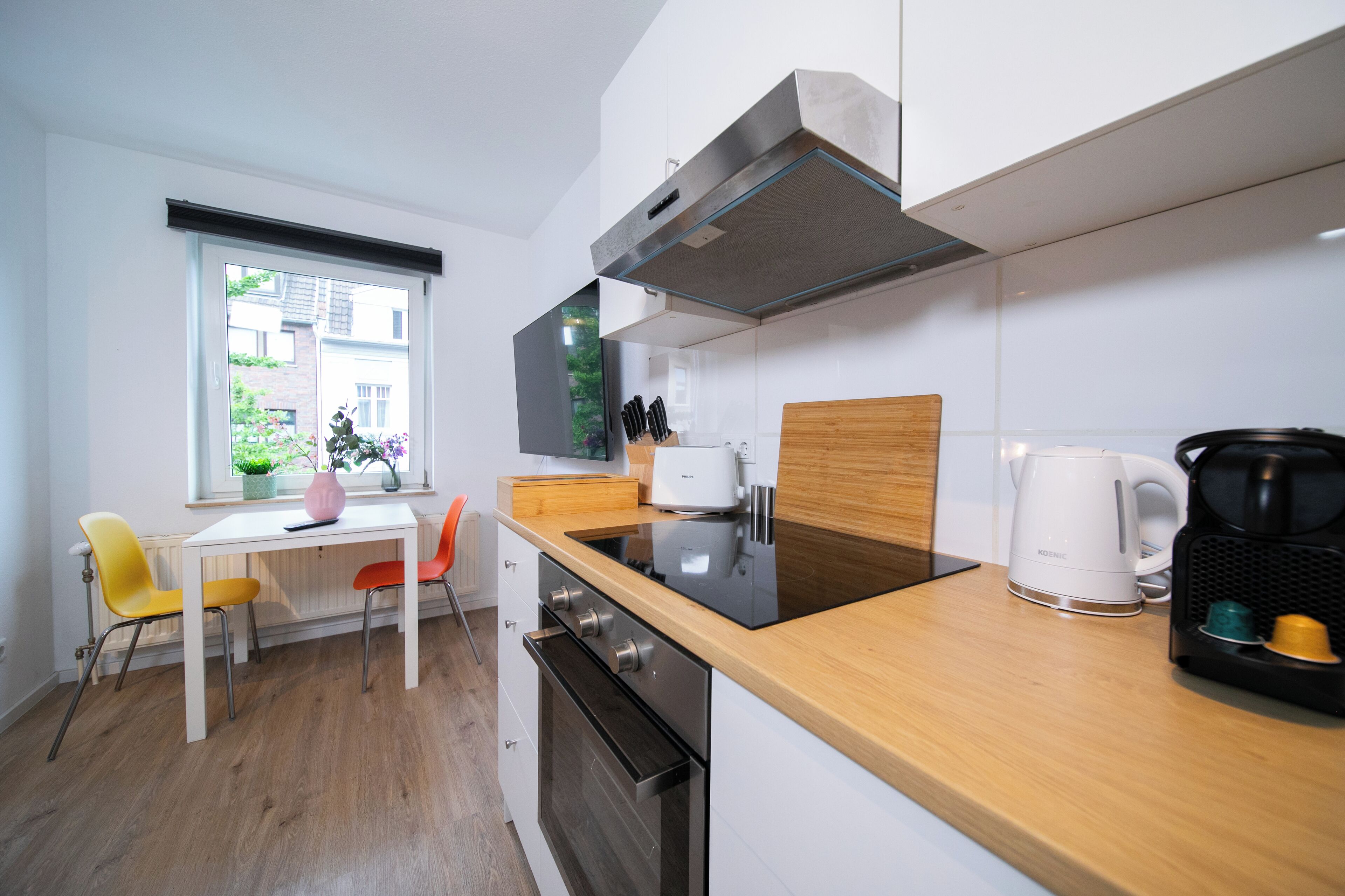 Eine moderne Küche mit einer Holzarbeitsplatte, einem eingebauten Backofen und einem Fenster mit Blick nach außen.
