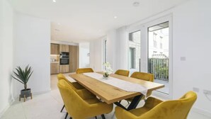 Un comedor moderno con una mesa de madera y sillas amarillas, una planta en maceta y vistas al exterior.
