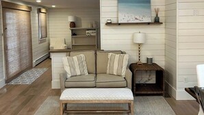 A cozy living room with a wooden bench, a sofa, and a painting on the wall. - Coastal home in Brewster near beaches and bike path RPMS161 (Brewtser)
